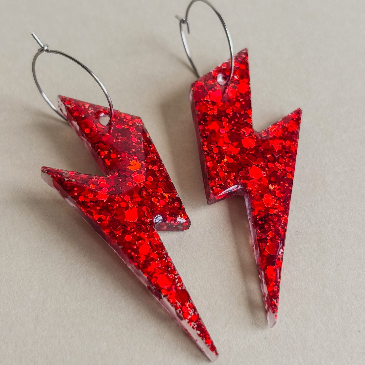 Pendientes de rayos rojos con mucho brillo y aros plateados sobre superficie plana