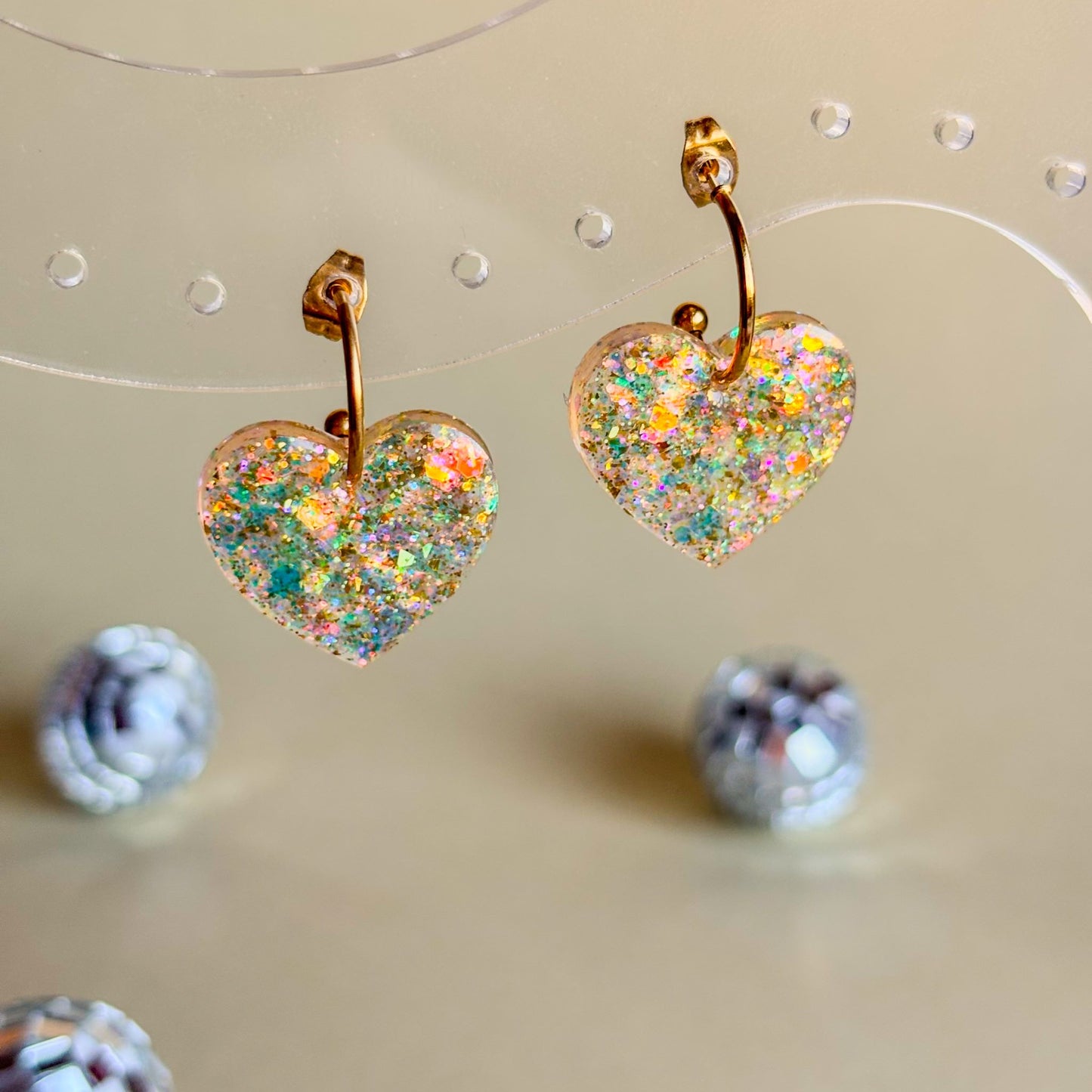 Expositor transparente con pendientes de corazones de color champán de resina epoxi