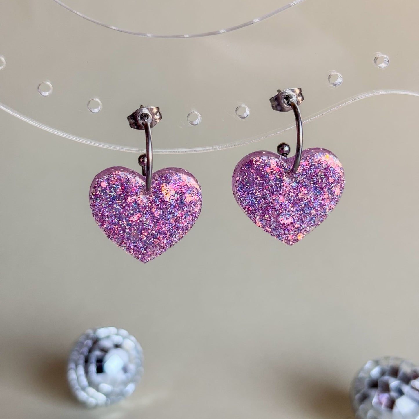 Expositor transparente con pendientes de corazones lila pastel muy brillantes