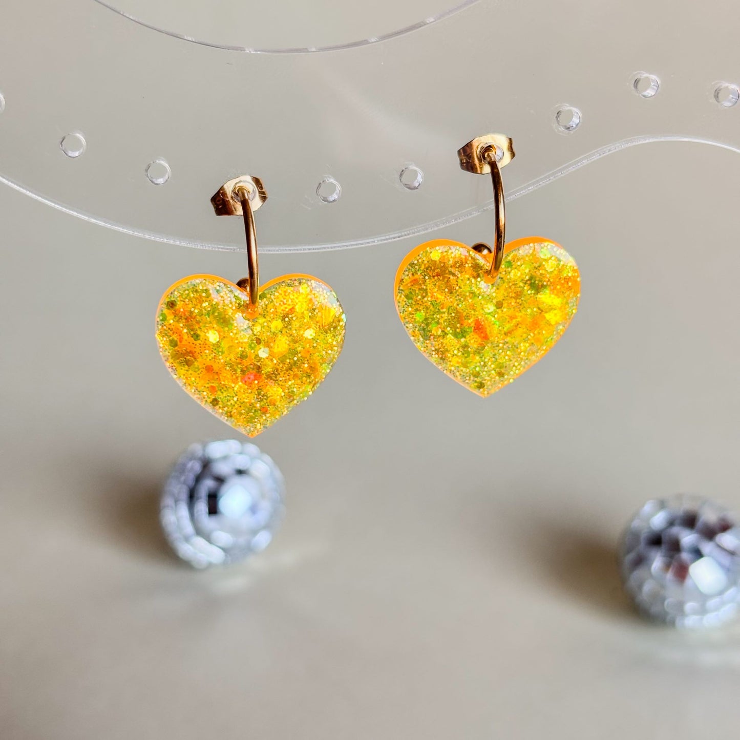 Pendientes de corazones brillantes naranjas en expositor transparente
