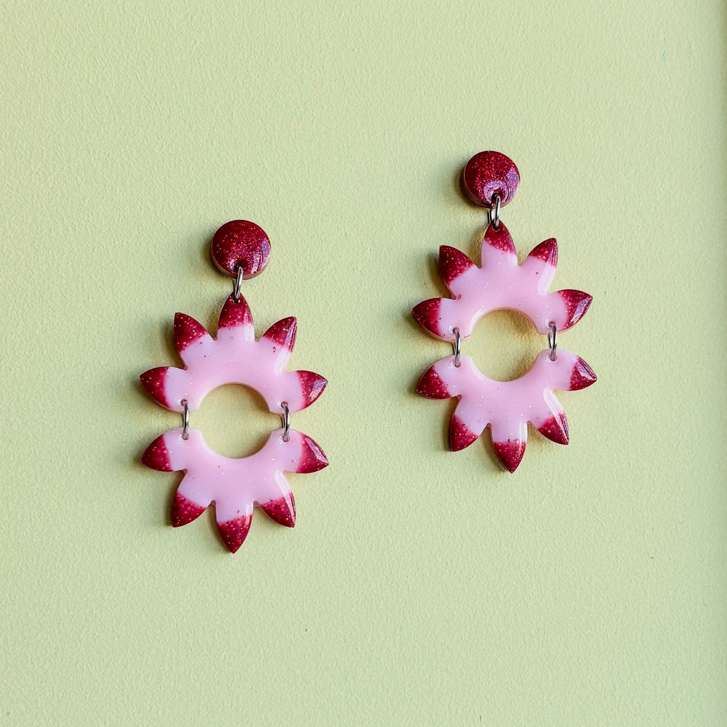 Par de pendientes artesanales de resina epoxi rosa pastel y rojo. Diseño vibrante y explosivo
