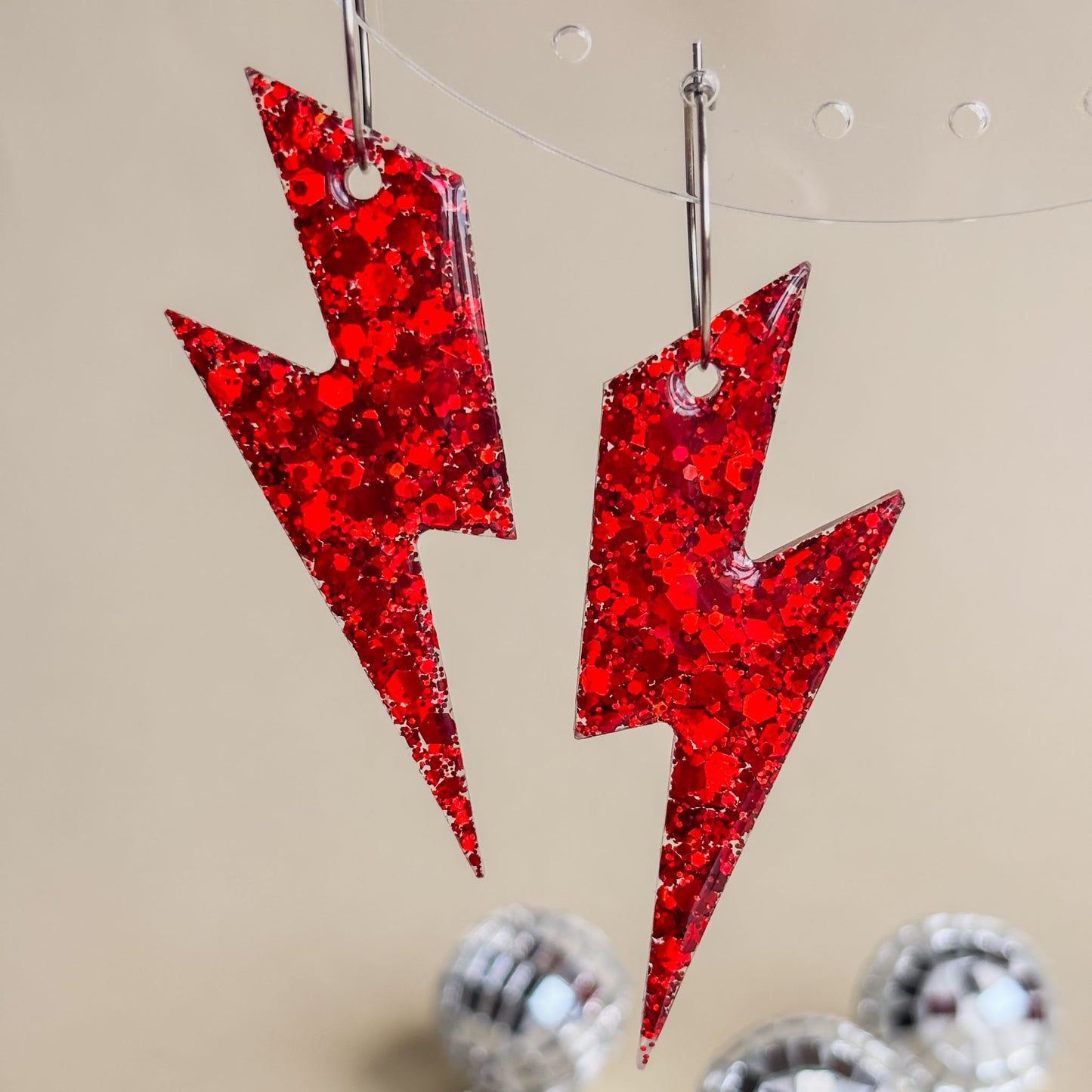 Pendientes de rayos rojos brillantes en expositor transparente