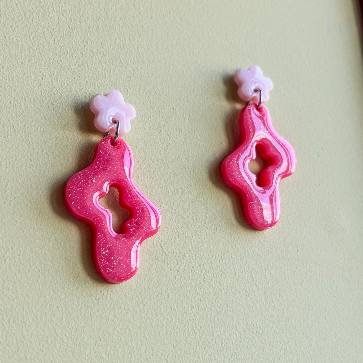 Pendientes con forma asimétrica ondulada color coral y pequeña pieza superior en forma de flor rosa pastel