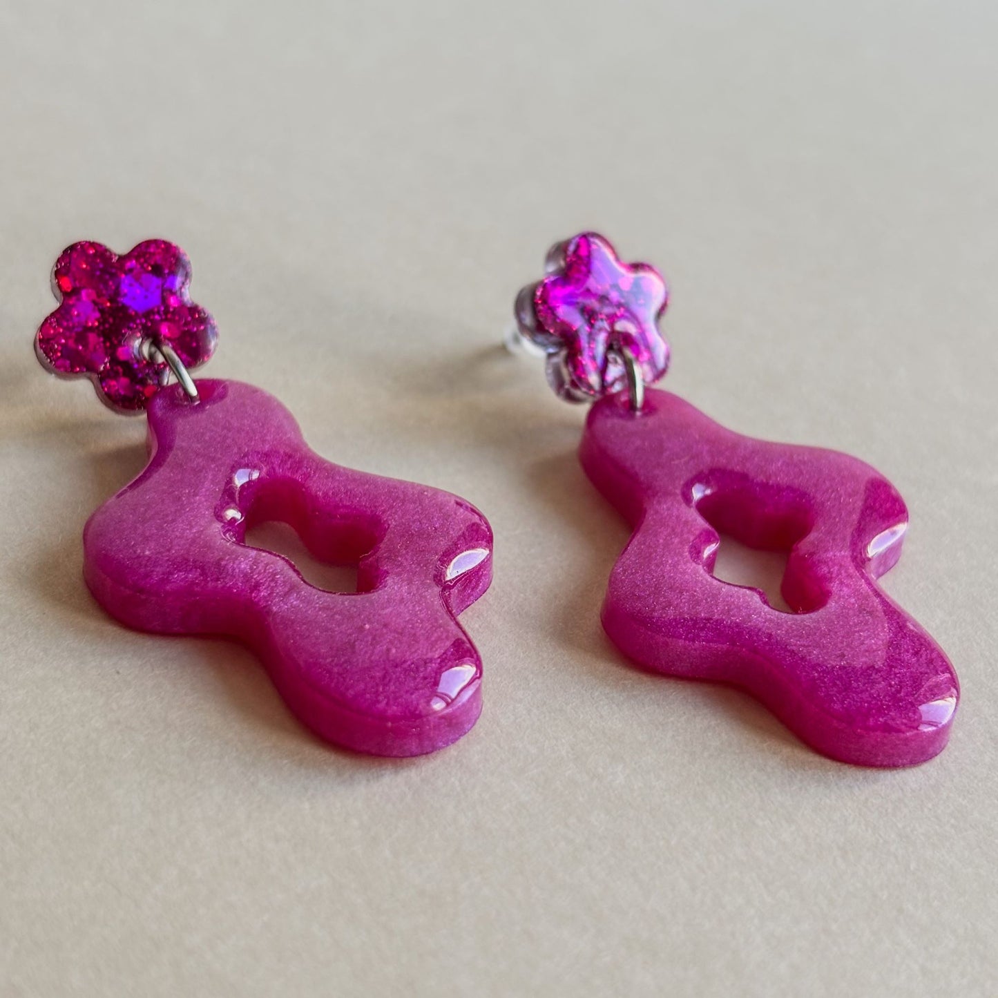Preciosos pendientes brillantes de color rosa y diseño ondulado con flor superior