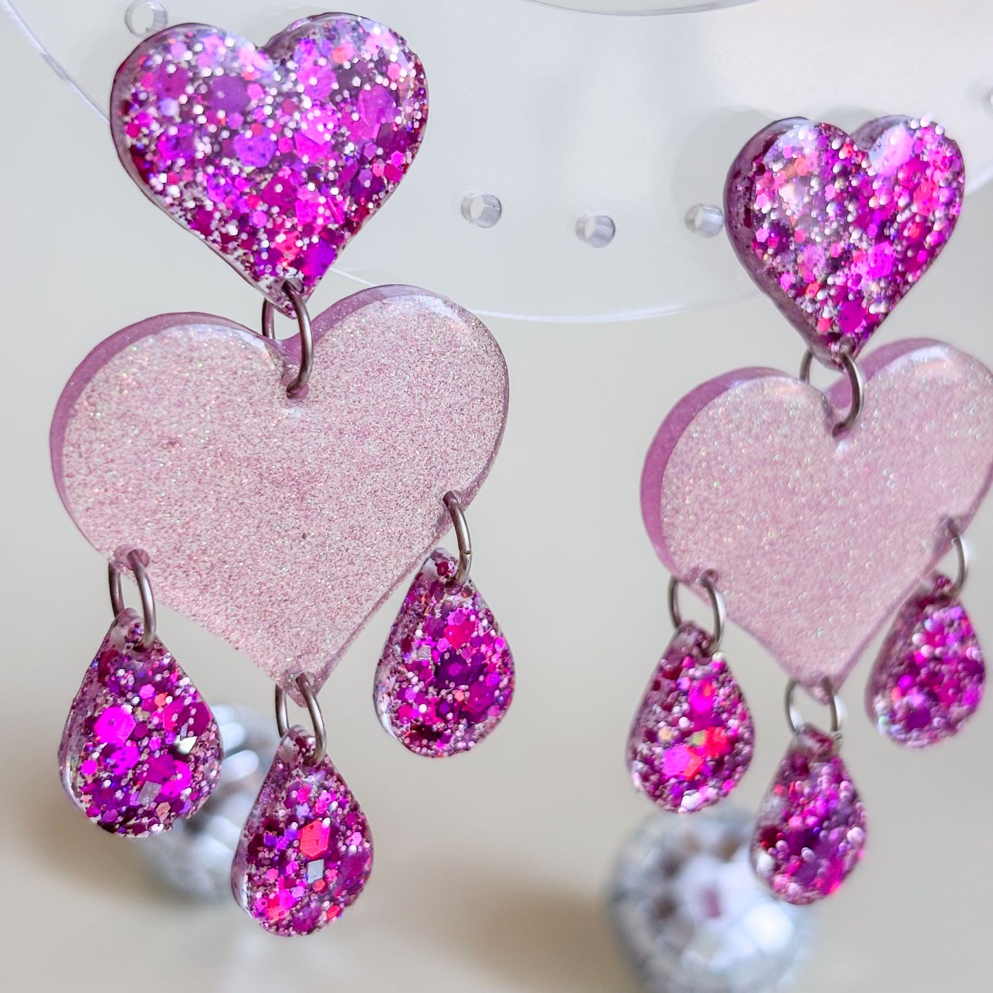 Pendientes hechos a mano con resina epoxi y acero inoxidable, con brillantina. Diseño de corazones y lágrimas. Marca española: Doctora Irrins