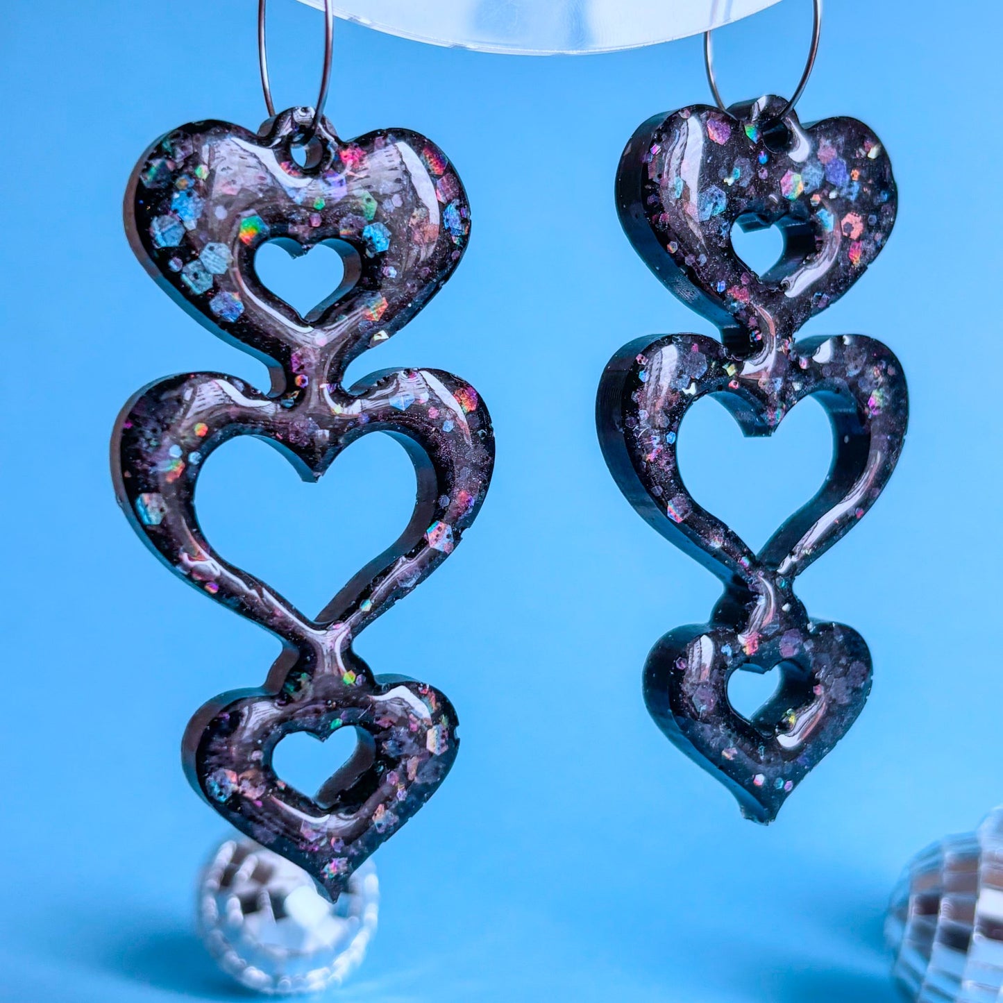 Pendientes artesanales grandes, de color negro, forma de corazones, brillantes. Hecho a mano con resina epoxi y acero quirúrgico. Marca española: Doctora Irrins