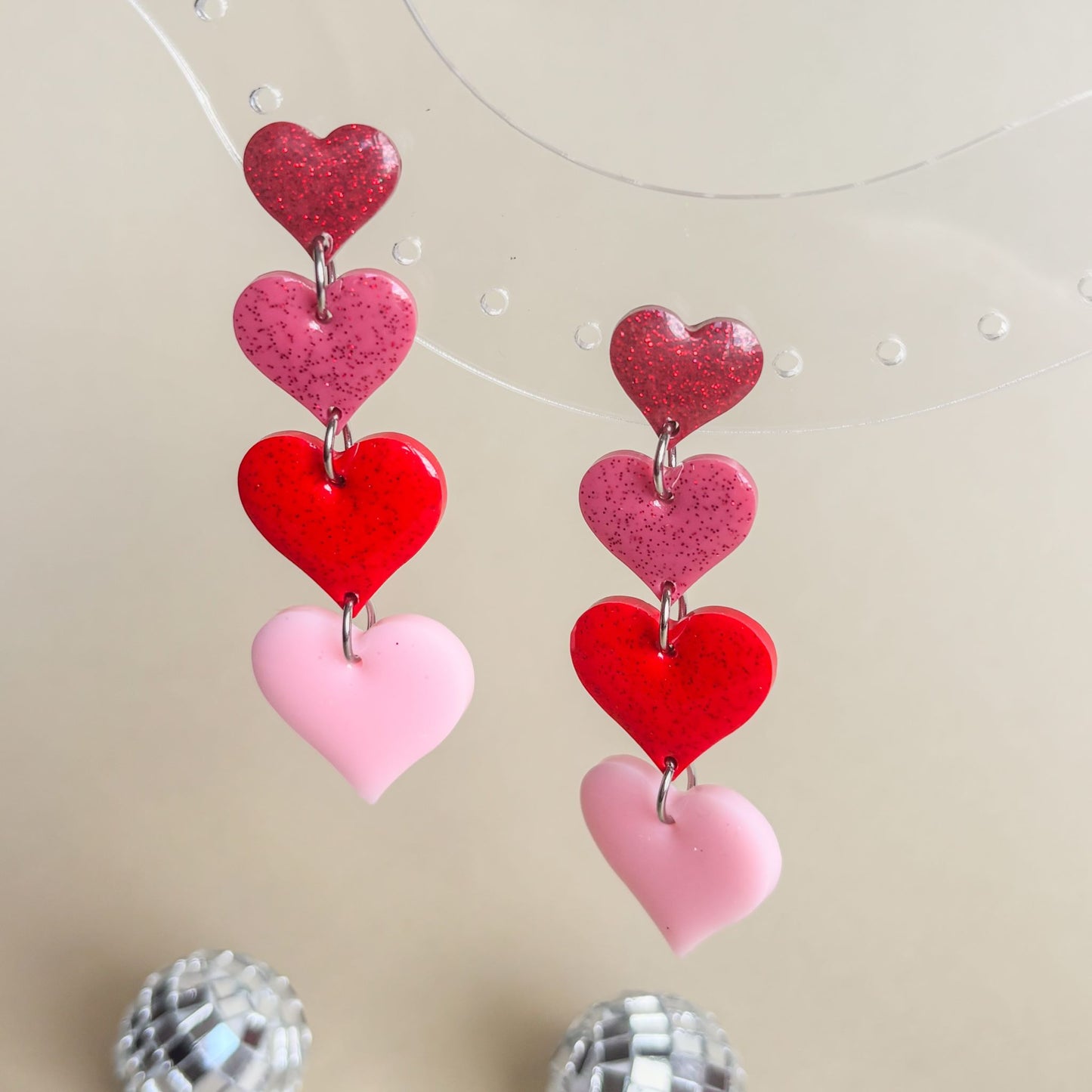 Pendientes largos de resina epoxi. Diseño de corazones en cascada de diferentes colores que van desde el burdeos hasta el rosa pastel. Marca española, Doctora Irrins