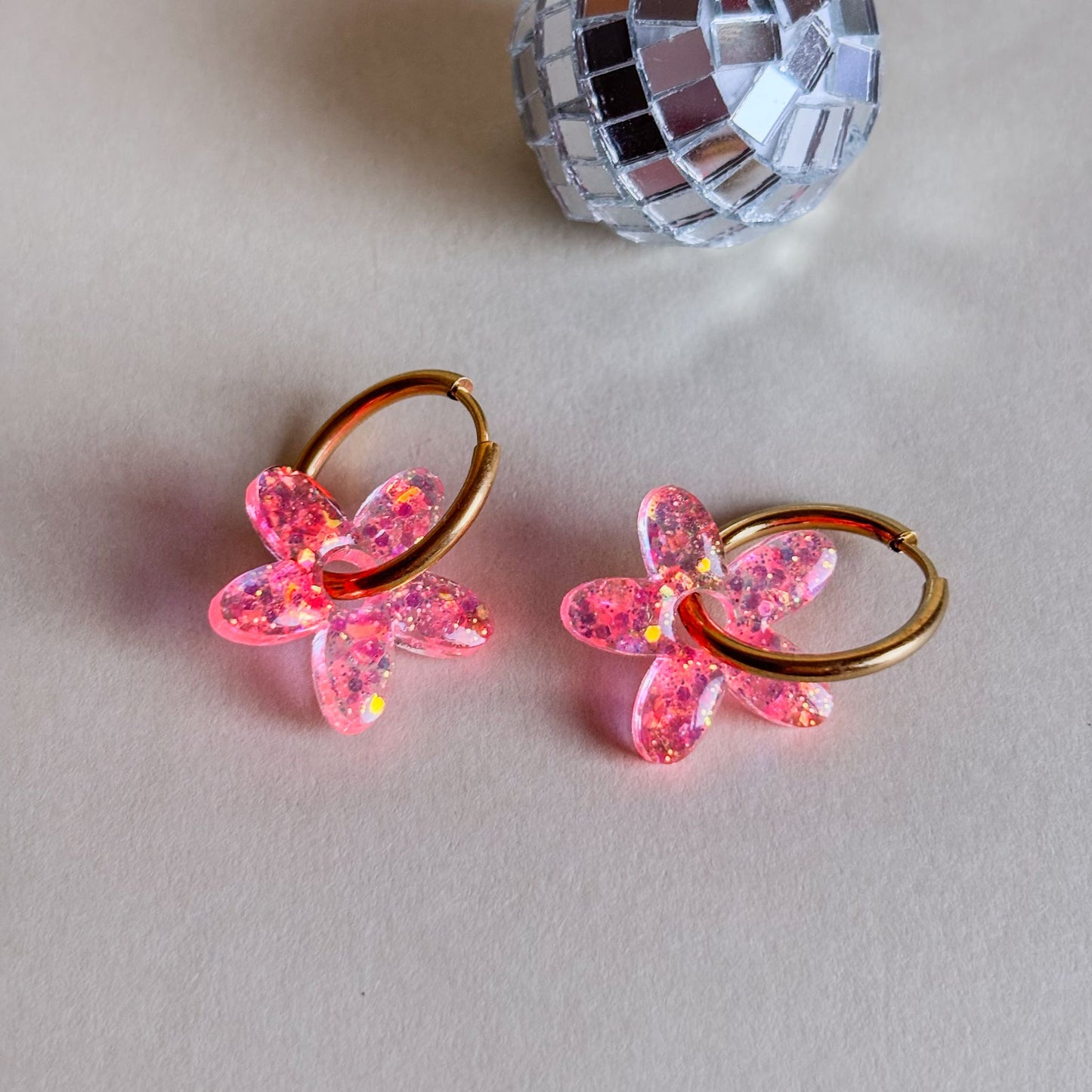 Pendientes de charms florales brillantes de color rosa con aros hipoalergénicos de acero inoxidable.