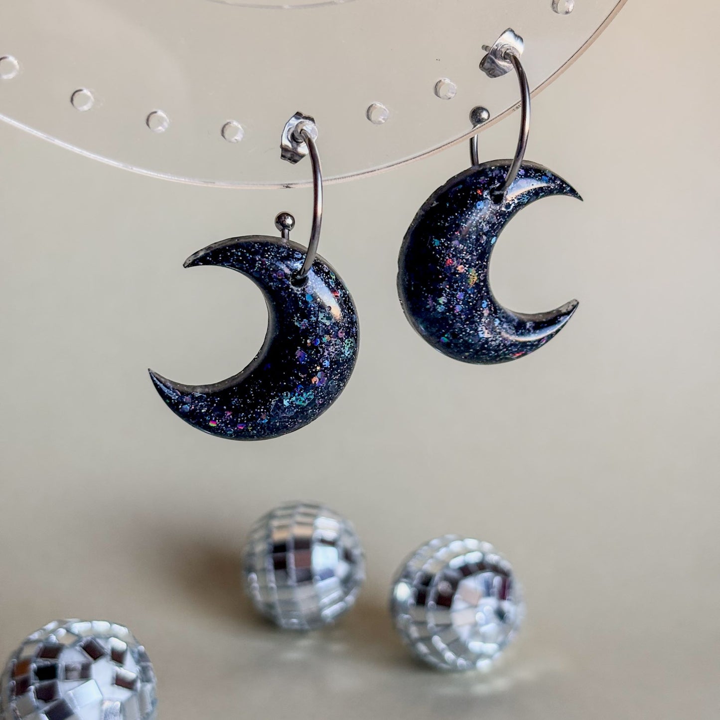Par de pendientes hipoalergénicos hechos a mano con forma de lunas negras colgando de aros plateados
