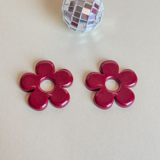 Pendientes de flores burdeos pegadas a la oreja