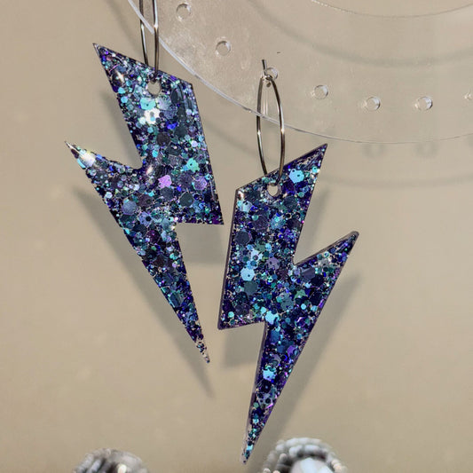 Pendientes en forma de rayos con un brillo impresionante de color azul y lila con luz de frente