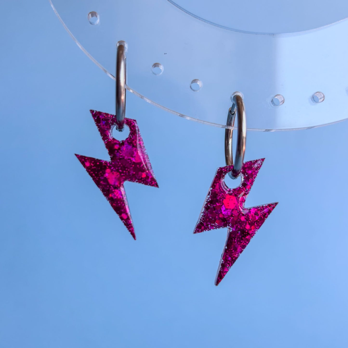 Pendientes en forma de rayo pequeños sobre un fondo azul cielo