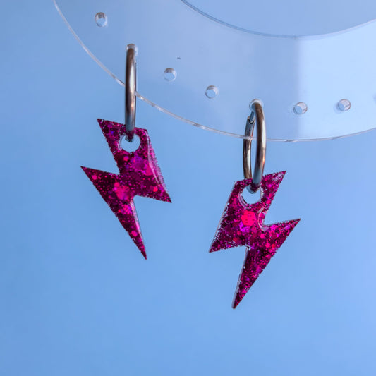 Pendientes en forma de rayo pequeños sobre un fondo azul cielo