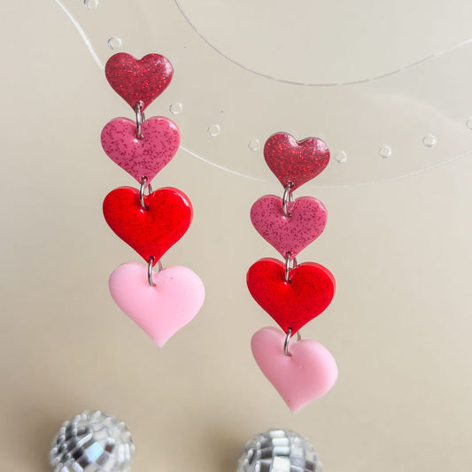 Pendientes largos de resina epoxi. Diseño de corazones en cascada de diferentes colores que van desde el burdeos hasta el rosa pastel. Marca española, Doctora Irrins