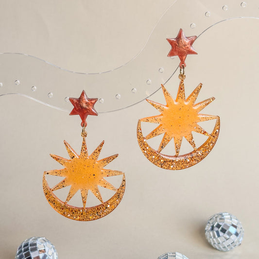 Pendientes naranjas y marrones en forma de estrella, sol y luna. 