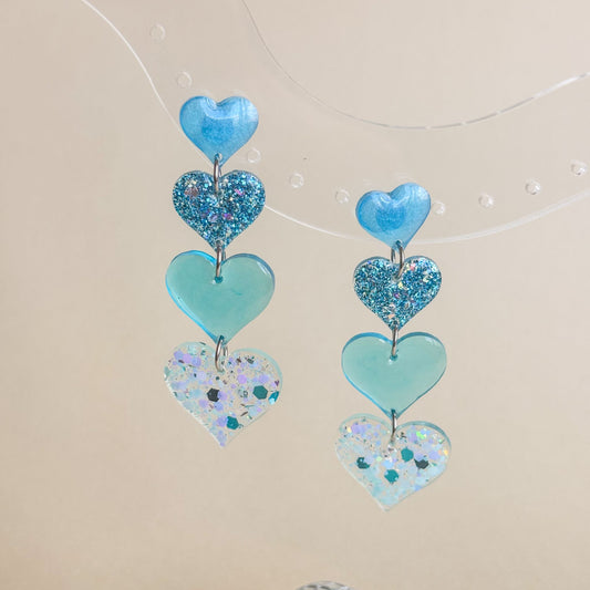 Par de pendientes artesanales con diseño de corazones en tonos azules. Hechos a mano e hipoalergénicos